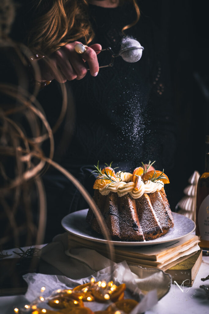 Candied orange-topped spice cake served on a marble cake stand, ready for a festive feast.