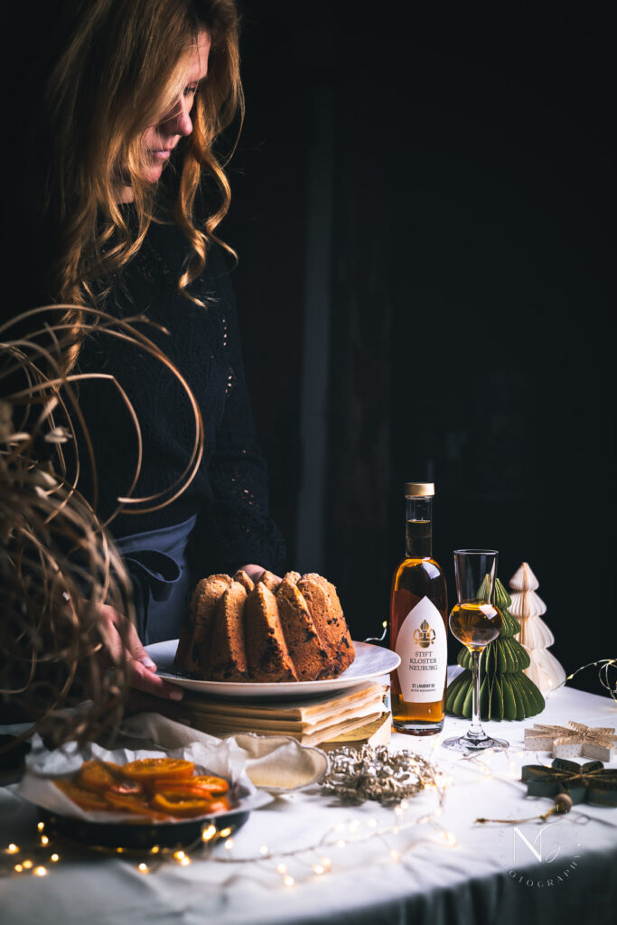 Festive dessert table featuring a spice cake with candied orange slices and a cup of coffee beside it.